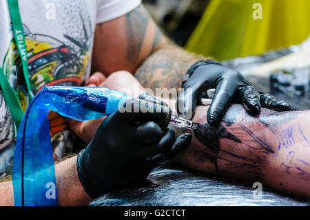 BELFAST, NORDIRLAND. 28 Mai 2016 - 6. Nordirland Tattoo-Konferenz. Ein Tattoo-Künstler zieht Tattoo auf dem Arm eines männlichen Kunden. Stockfoto