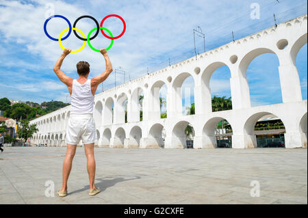 RIO DE JANEIRO - 29. März 2016: Sportler der Olympischen Ringe steht im Freien in der Plaza in der legendären Arcos da Lapa Bögen halten. Stockfoto