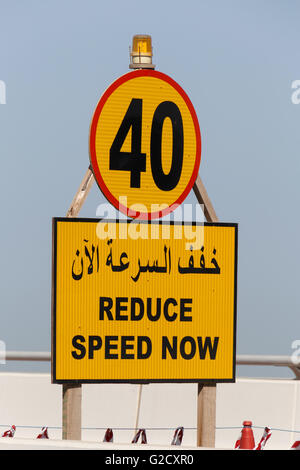 Verkehrszeichen verringern Geschwindigkeit jetzt auf Englisch und Arabisch Stockfoto