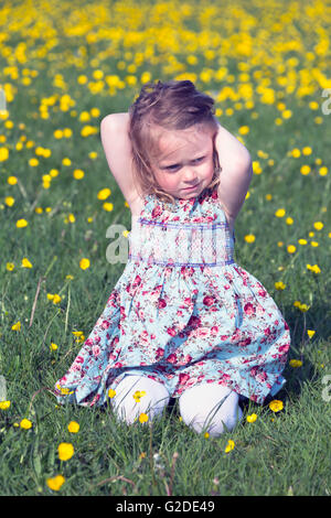 ein 3-jähriges Mädchen sitzt auf einer Blumenwiese Stockfoto