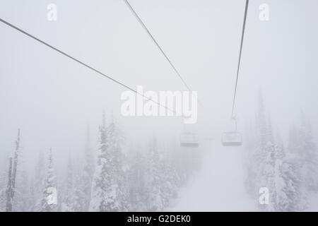 Neblig verschneiten Bäumen und Ski-Sessellift in Ferne Stockfoto