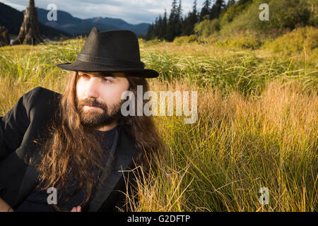 Bärtiger Mann in Hut und Anzugjacke Entspannung in Grass, Nahaufnahme Stockfoto