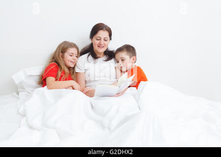 Mutter für ihr Kind vor dem Einschlafen ein Buch im Bett lesen Stockfoto