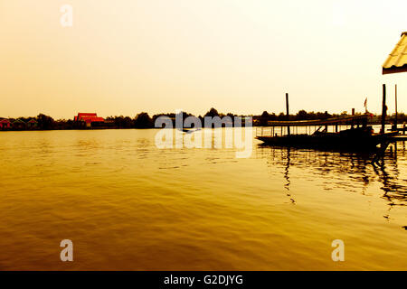 Lange Holz-Boot Heckmotor im Fluss in der Morgendämmerung mit goldenem Licht. Sonnenaufgang mit silhouette Stockfoto