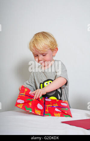 Kleiner Junge ein Geburtstagsgeschenk zu öffnen Stockfoto