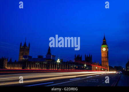 Palast von Westminster in London und dem Big Ben in der Nacht mit Fahrzeug hinterließ eine Schneise entlang der Straße, mit einem klaren blauen Himmel. Stockfoto