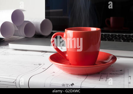 Architekten zeichnen Baupläne mit einem silbernen Laptop mit roten Tasse Kaffee Stockfoto