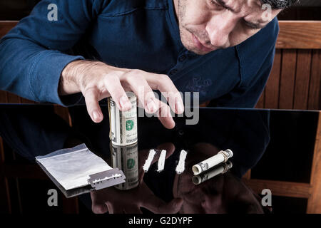 Mann packte weißen Droge Zeilen mit aufgerollt Dollar Banknote auf dunklen mit Reflexion Stockfoto