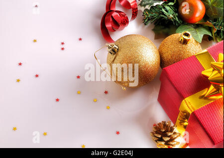 Weihnachts-Dekoration auf einem weißen Methacrylat-Tisch. Rotes Geschenk box mit Goldband, zwei Goldene Kugeln und andere Objekte. Ansicht von oben Stockfoto