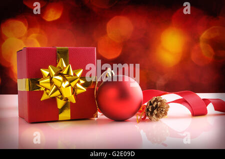 Rot Weihnachten Dekoration auf einer weißen Tafel Methacrylat. Mit Geschenk-Box mit gold Band, Ball, Tannenzapfen und Tuch Band. Vorderansicht Stockfoto