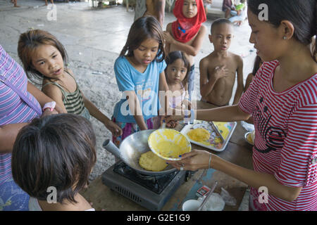 Menschen, die auf Friedhöfen ist nicht ungewöhnlich in der Philippines.Here ein junges Mädchen kocht Pfannkuchen für die Friedhof-Community. Stockfoto