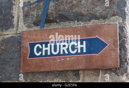 alte braune Holz Kirche Schild mit blauer Pfeil auf dunklen Stein Wand Stockfoto