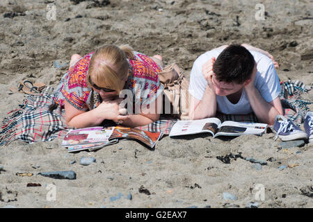 Aberystwyth Wales UK, Sunday 29 May 2016  UK Bank Holiday weather; On a fine sunny and very warm Sunday afternoon, a couple read their magazines and enjoy the sunshine on the beach  in Aberystwyth on the coast of Cardigan Bay, west Wales.  The temperature is set to reach 22ºc by the mid afternoon, and the fine weather is forecast to continue into the Bank Holiday Monday in the west, though with the threat of rain in the south east of the UK   photo Credit:  Keith Morris / Alamy Live News Stockfoto