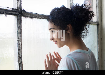 Glückliche junge Frau aus dem Fenster Stockfoto