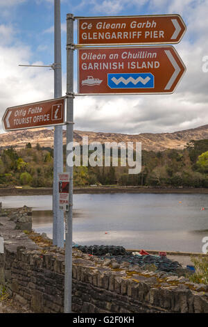 Zweisprachige Wegweiser zeigt den Weg zum garnieren Island Ferry, TIC und Glengarriff Pier in Englisch und Gälisch, Co. Cork, Irland. Stockfoto