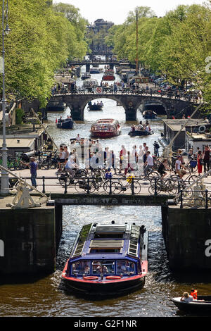 Amsterdamer Grachten. Vier Brücken mit vielen Radfahrern an der Prinsengracht Kanal mit Tour Hausboote und kleine Sportboote im Frühjahr Stockfoto