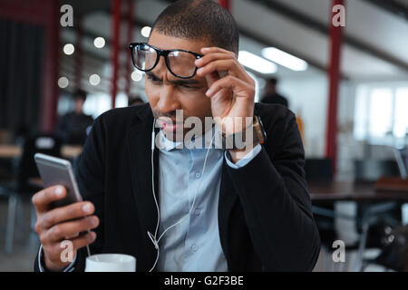 Intelligente Busineessman berühren seine Brille und Nachricht auf dem Smartphone lesen Stockfoto