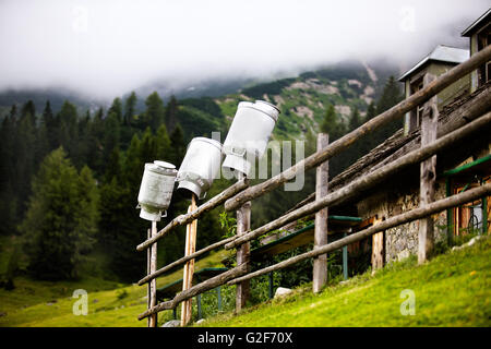 Dosen im Alpine Chalet in den europäischen Alpen fixiert auf dem Zaun nach der Reinigung Milch darauf warten, wieder aufgefüllt werden Stockfoto