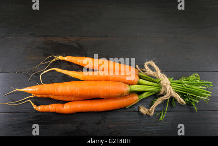Frischen Karotten Strauß auf einem dunklen Holzbrett Stockfoto