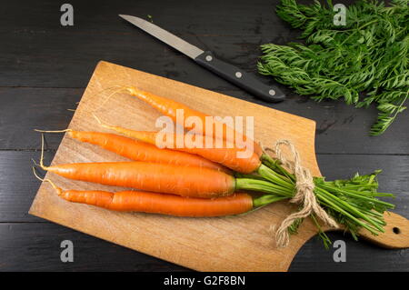 Frischen Karotten Strauß auf einem dunklen Holzbrett Stockfoto