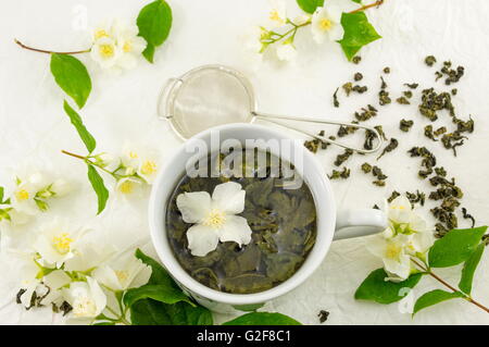 Grüner Tee mit Jasmin Blatt in eine Tasse auf Seidenstoff Stockfoto