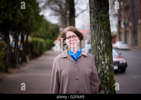 Lächelnde Frau mittleren Erwachsenenalter im Trenchcoat Stockfoto