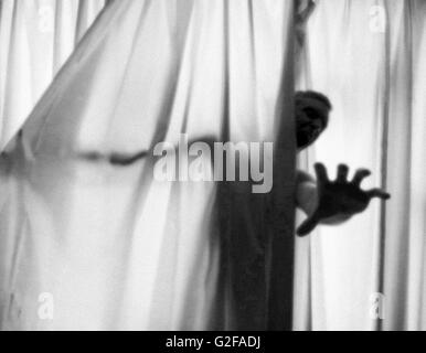 Schreienden Mann Hand ausstrecken von Vorhängen Stockfoto