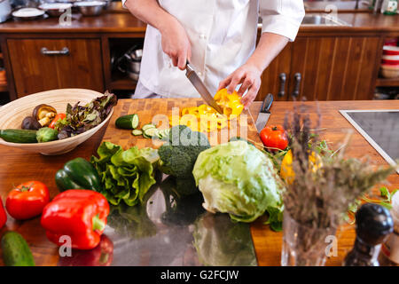 Nahaufnahme von Chef-Koch stehen und machen Salat auf dem Küchentisch Stockfoto