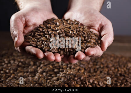 Männliche Arbeiter Hände halten frisch gerösteten dunkle Espresso Kaffeebohnen Stockfoto