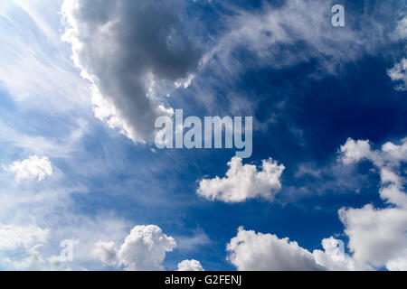 Weiße Cumulus-Wolken und graue Wolken am blauen Himmel Stockfoto