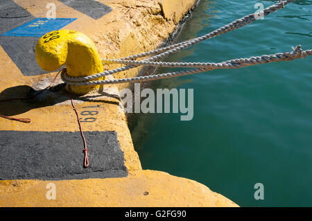 Gelbe konkrete Liegeplatz Klampe mit Seil gebunden um am Hafen von Piräus in Athen, Griechenland. Stockfoto