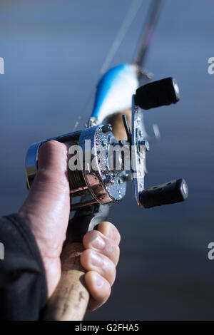 Männliche Hand auf einem nassen Runde Angelrolle Stockfoto