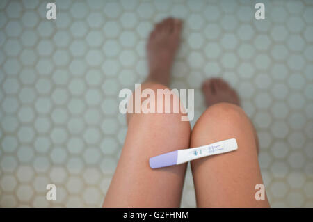 Positiven Schwangerschaftstest auf Frauenbeine in Badezimmer, High Angle View Stockfoto