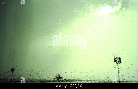 Biker im Regen gesehen durch Windschutzscheibe Stockfoto