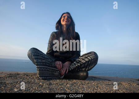 Lächelnde Frau sitzen auf Sea Cliff Stockfoto