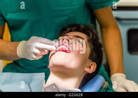 Mann auf dem Zahnarztstuhl während der Kieferorthopäde die zahnärztliche Gerät überprüft Stockfoto