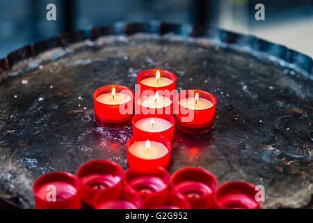 votive-Kerzen bilden das Symbol des Kreuzes Stockfoto