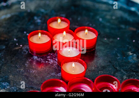 votive-Kerzen bilden das Symbol des Kreuzes Stockfoto