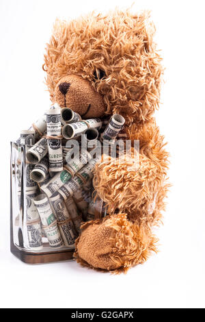 Brauner Teddybär hält Glas voll mit gerollten-Dollar-Banknoten isoliert auf weißem Hintergrund Stockfoto