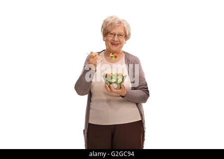 Studioaufnahme von einer älteren Frau Essen einen Salat und schaut in die Kamera, die isoliert auf weißem Hintergrund Stockfoto
