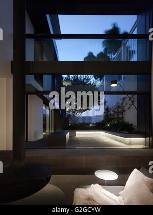 Blick vom Wohnzimmer zum Hof in der Abenddämmerung. W-House, Sydney, Australien. Architekt: MCK Architekten, 2015. Stockfoto