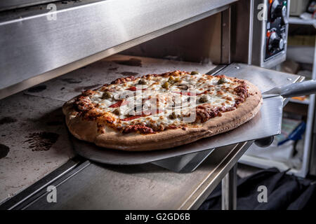 Pizza machen Closeup mit grünen Oliven, Paprika und Käse im Ofen Stockfoto