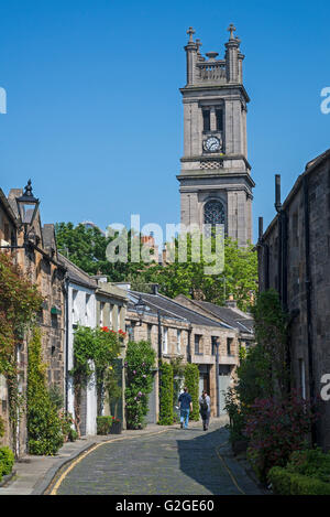 Ein paar spazieren Zirkus Gasse mit dem Turm der St. Stephen Kirche im Hintergrund - Stockbridge, Edinburgh. Stockfoto