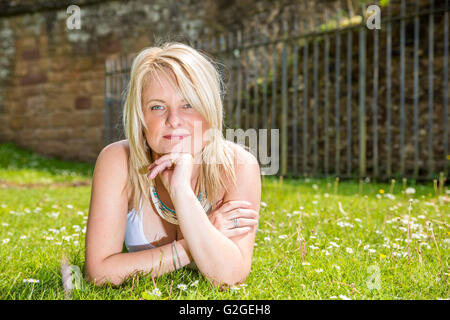 Eine blonde hübsche Frau in der Wiese liegend Stockfoto