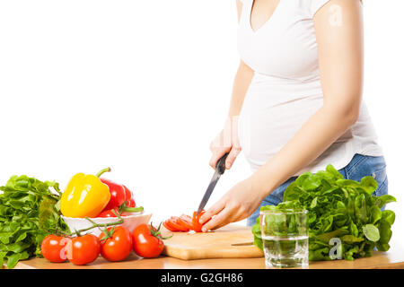 Nahaufnahme der schwangeren Frau schneiden Tomate Stockfoto