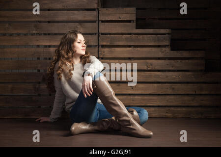 Junge langhaarige Brünette am Boden wegschauen Stockfoto