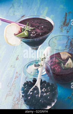 Schwarzen Johannisbeeren Dessert, Smoothie, lokale organische gefrorene Johannisbeeren und Margarita cocktail in ein Glas auf einem blauen rustikalen Tisch Stockfoto