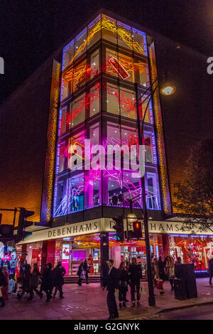 Leute, die an Weihnachten an Debenhams Kaufhaus in der Oxford Street vorbeigingen, das mit Weihnachtslichtern in London, Großbritannien, dekoriert wurde Stockfoto