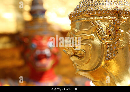 Goldene Kinnara Staue und Yaksha Dämon an der Wat Phra Kaeo Tempelanlage in Bangkok, Thailand Stockfoto