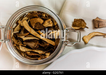 Getrocknete Pilze in Glasflasche auf dem weißen Tuch Stockfoto